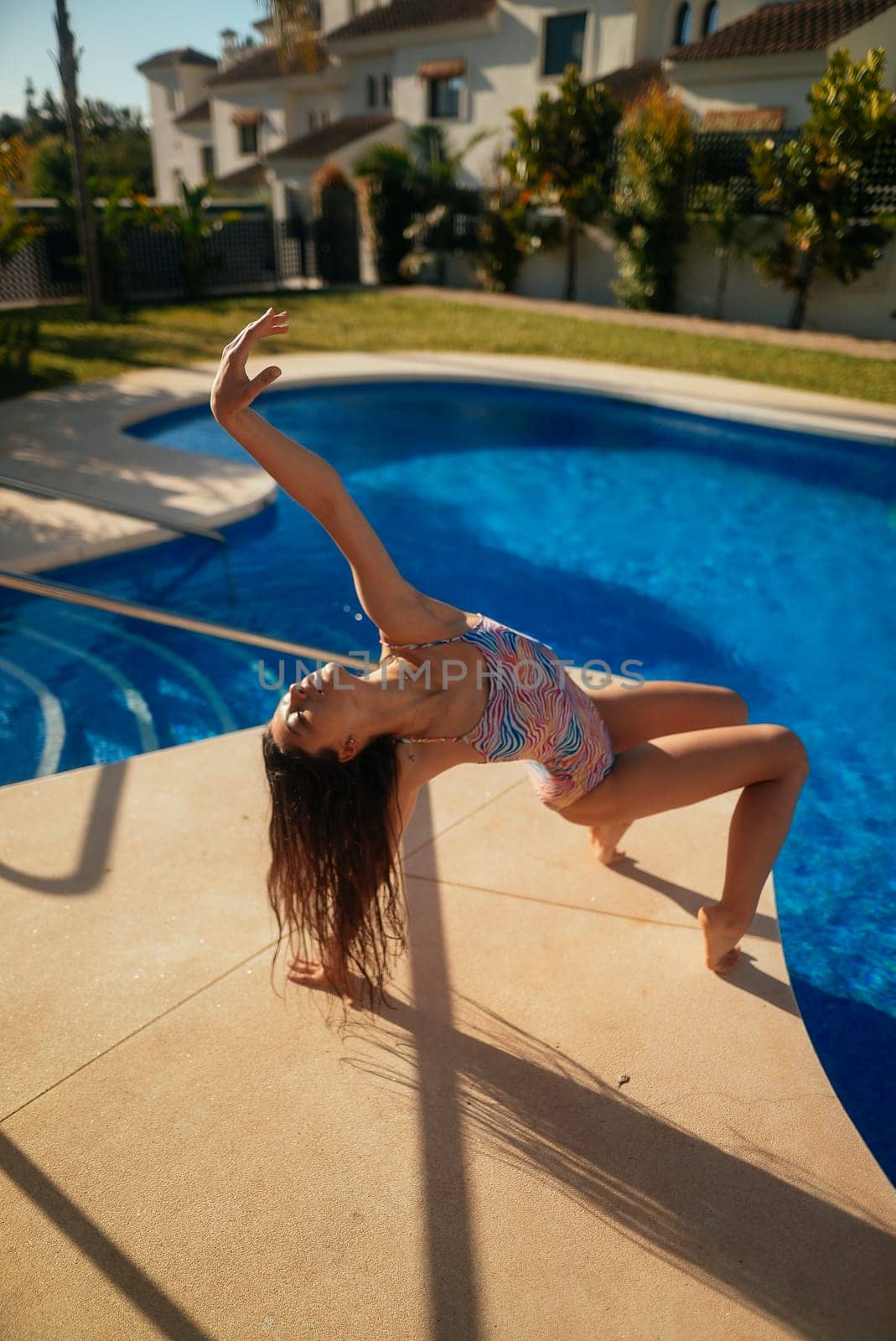 A captivating and skilled dancer, gracefully performing an elegant pose by a beautiful and serene poolside