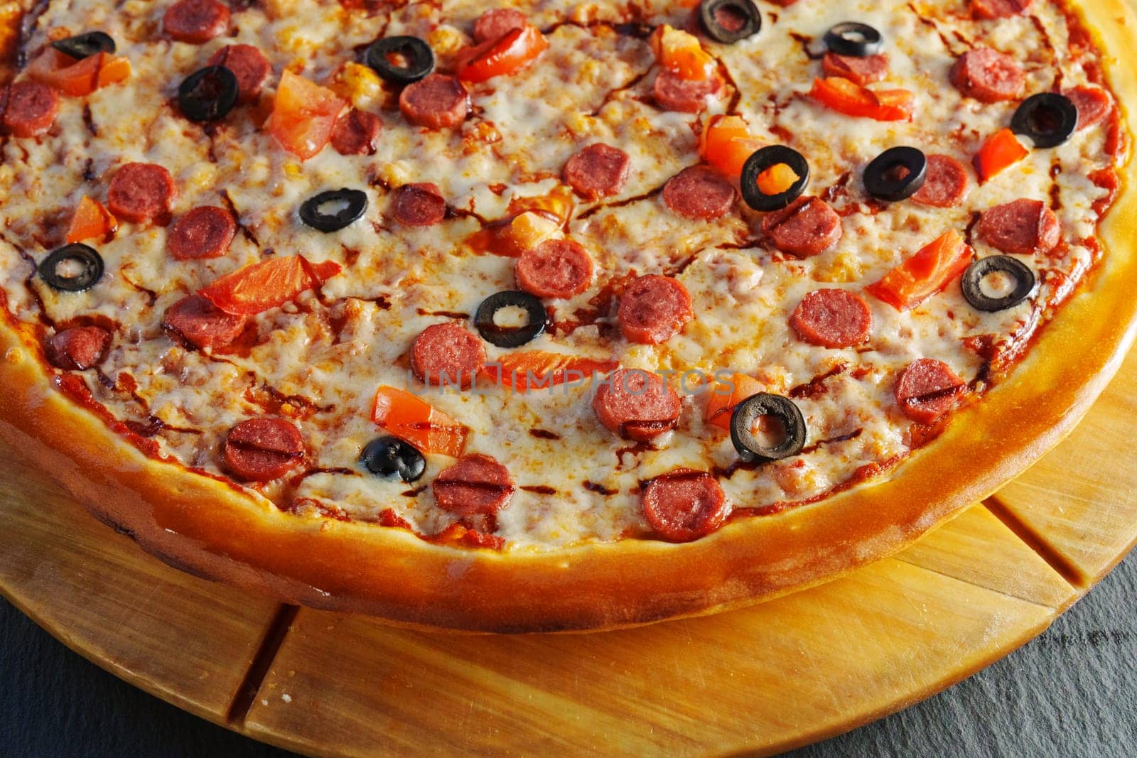 A delicious pepperoni pizza topped with olives and tomatoes served warm on a wooden board ready for sharing at a cozy gathering