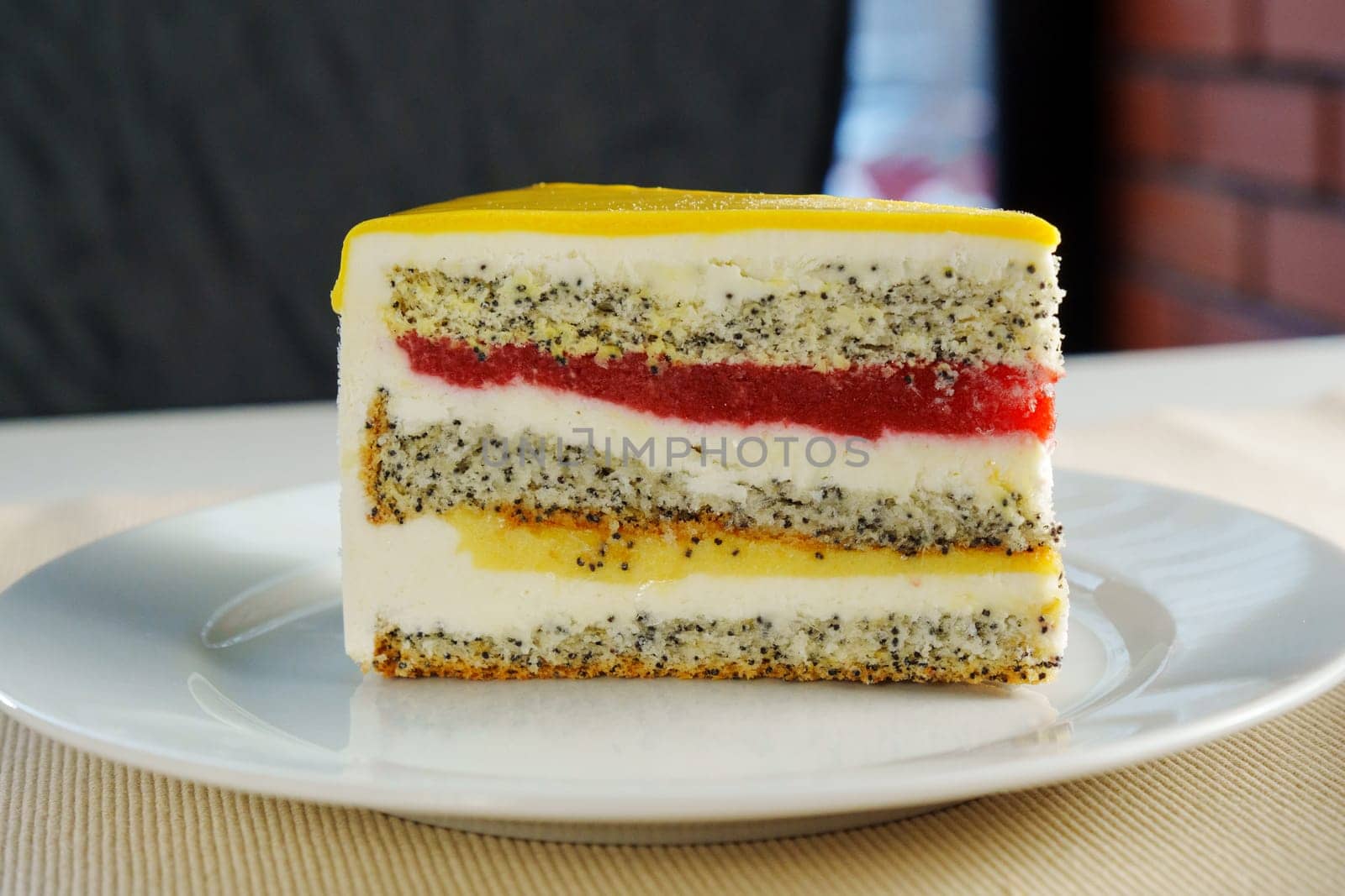 This delightful treat celebrates layers of poppy seed cake, rich cream, and bright fruit jelly, inviting indulgence on a cheerful afternoon gathering.