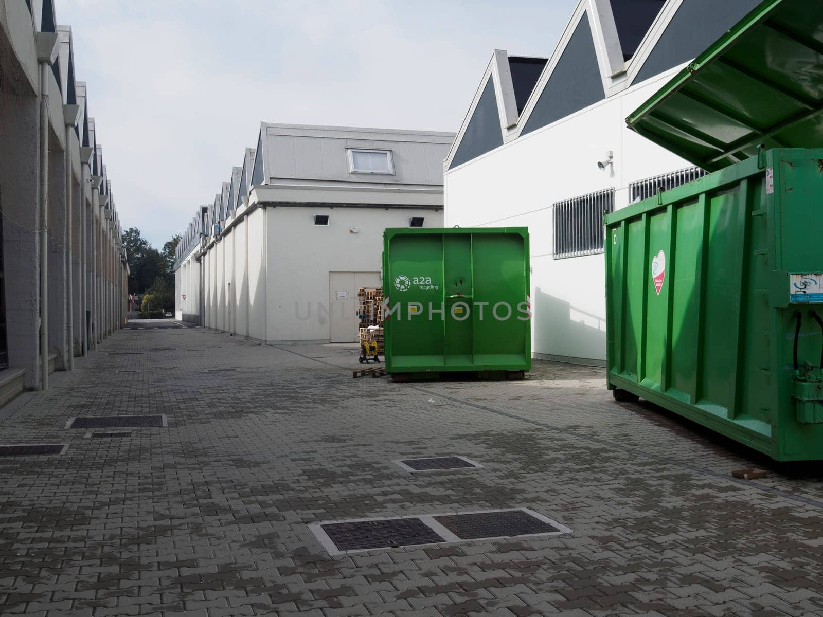 Cremona, Italy August 31st 2024 Large industrial green waste compactor machine with an electric cable plugged in, parked outdoors on a paved area