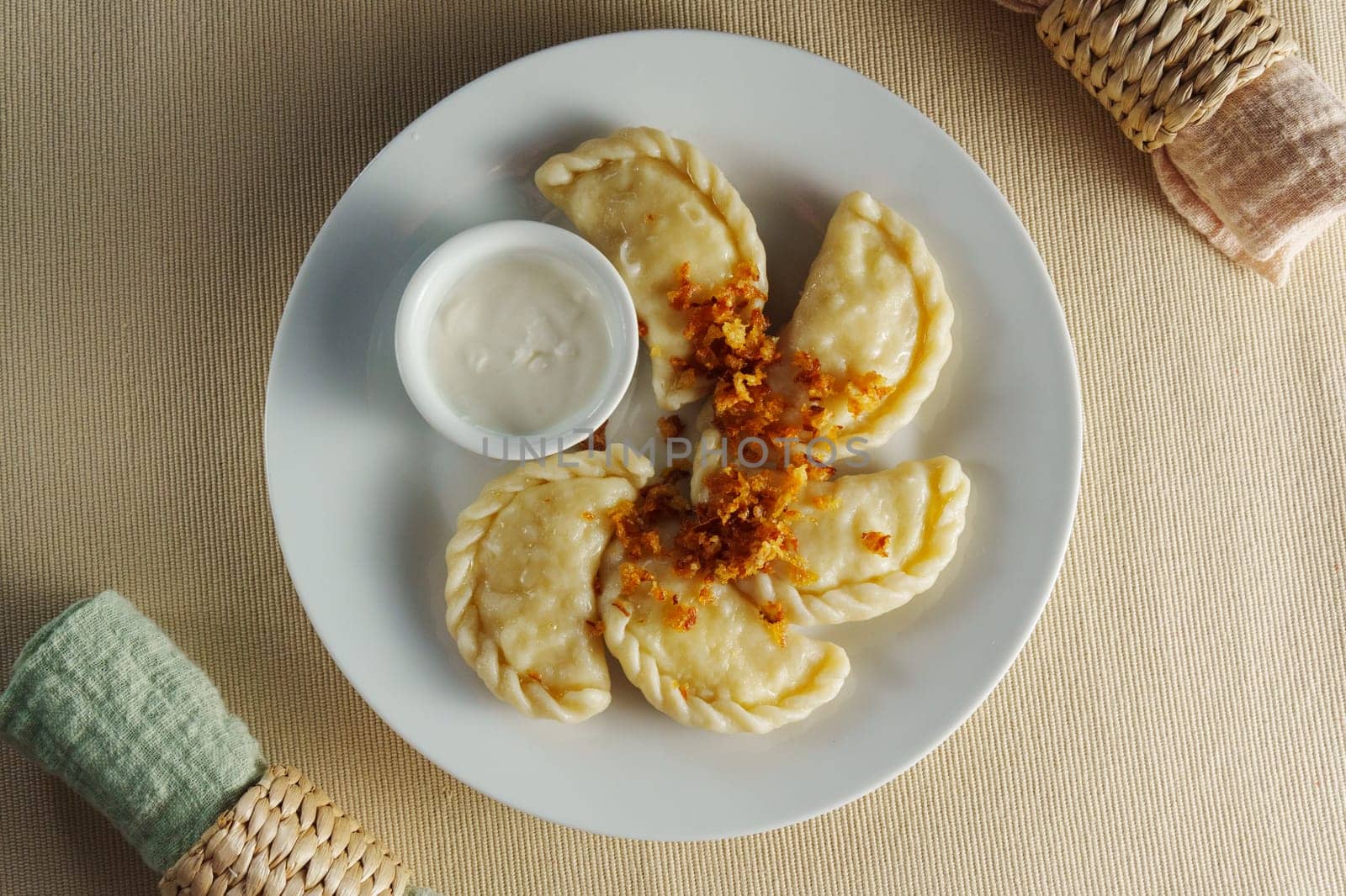 Savory homemade dumplings garnished with crispy toppings served with a creamy dip on a rustic table