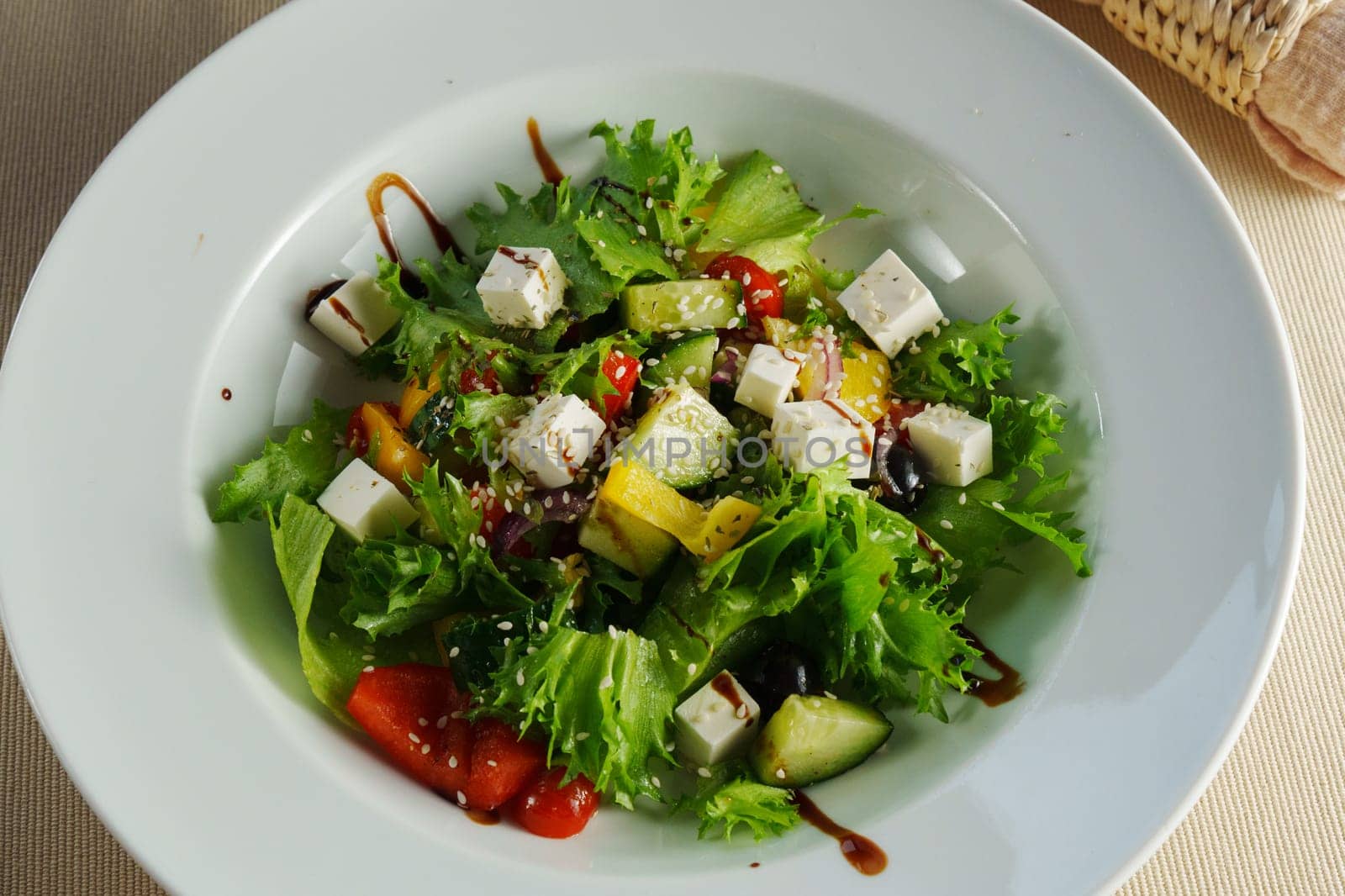 A vibrant salad with fresh greens, cherry tomatoes, cucumbers, and feta cheese drizzled with balsamic dressing on a sunny afternoon