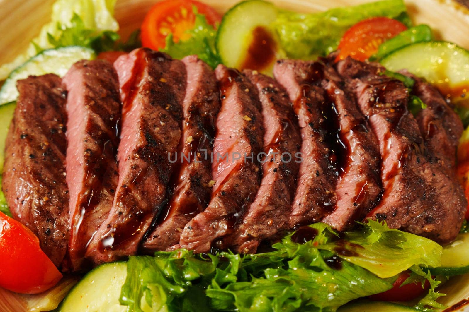Succulent grilled steak is sliced and gently placed atop a colorful mix of crisp greens and juicy tomatoes