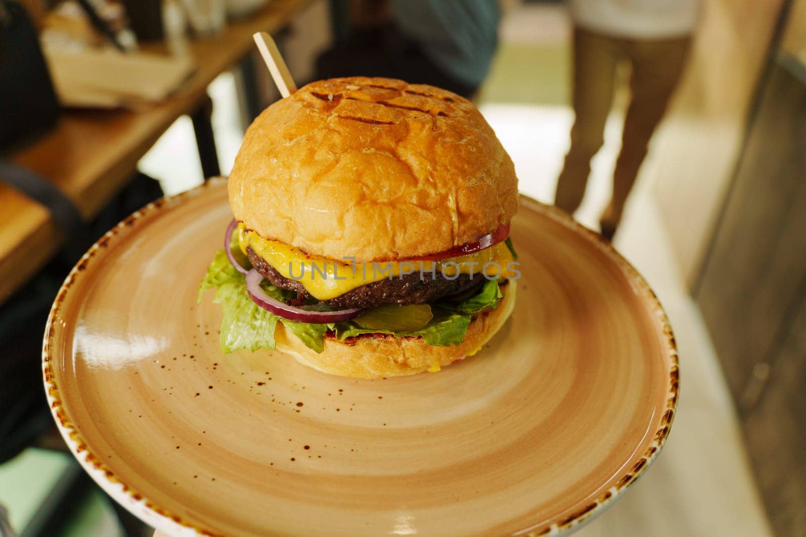 A mouthwatering cheeseburger stacked high with fresh toppings, nestled on a rustic plate ready to be enjoyed in a cozy setting