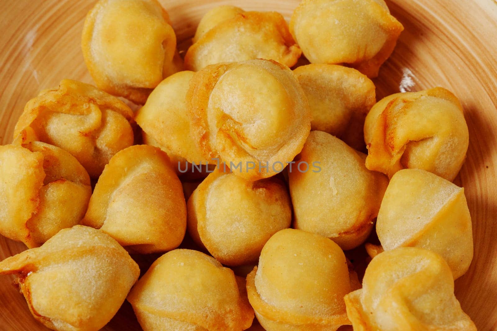 Golden dumplings arranged artfully in a wooden bowl, showcasing their crispy texture and inviting aroma on a sunny afternoon