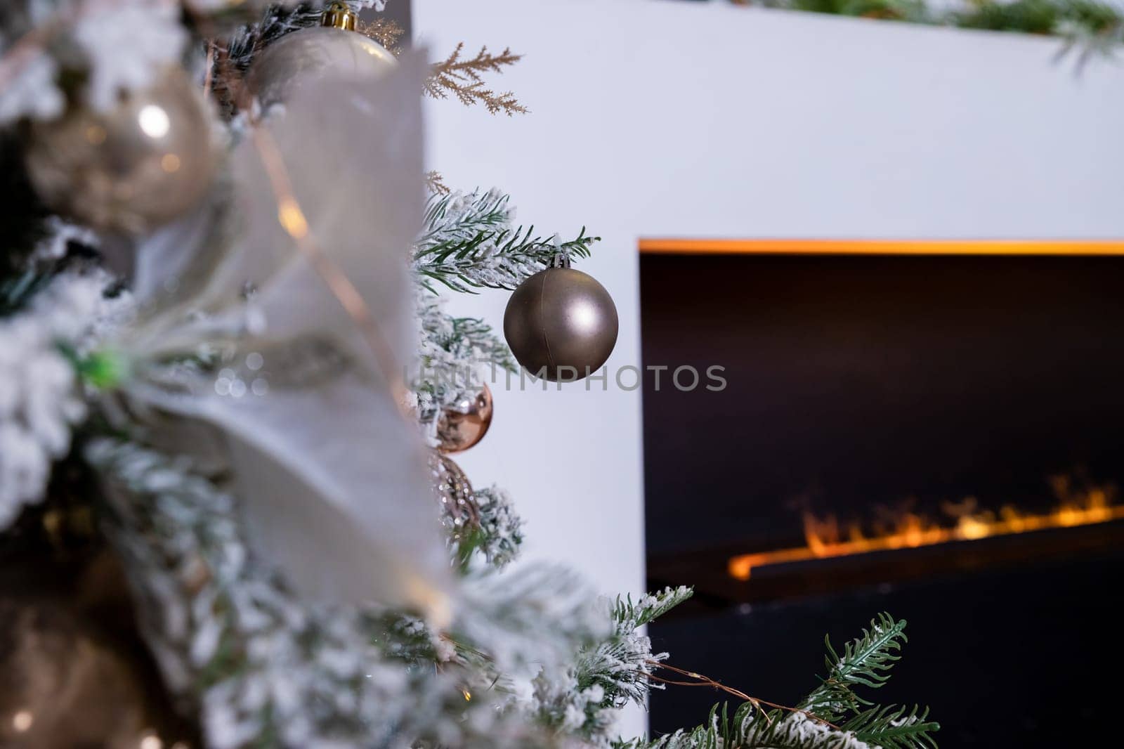 Christmas tree decorated with lovely ornaments and classical style fireplace in white room. New year scene.
