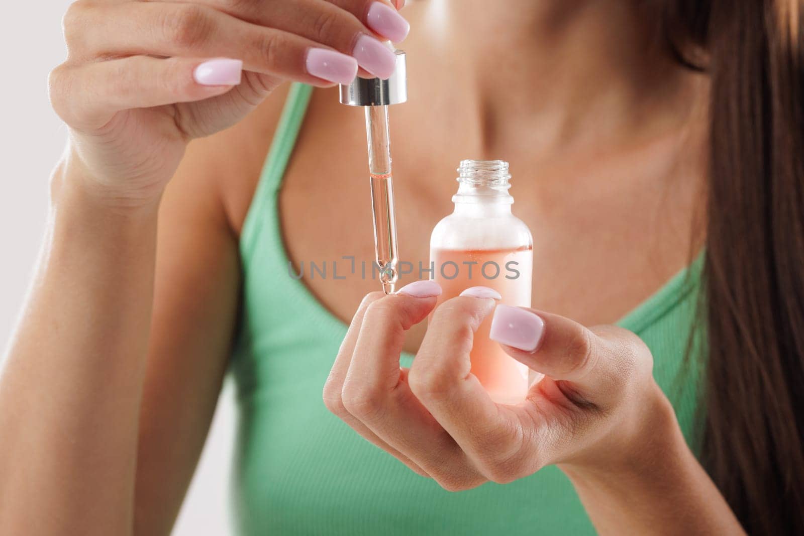 woman applying organic oil on cuticles with pipette close-up, hand care concept, healthy nails and skin