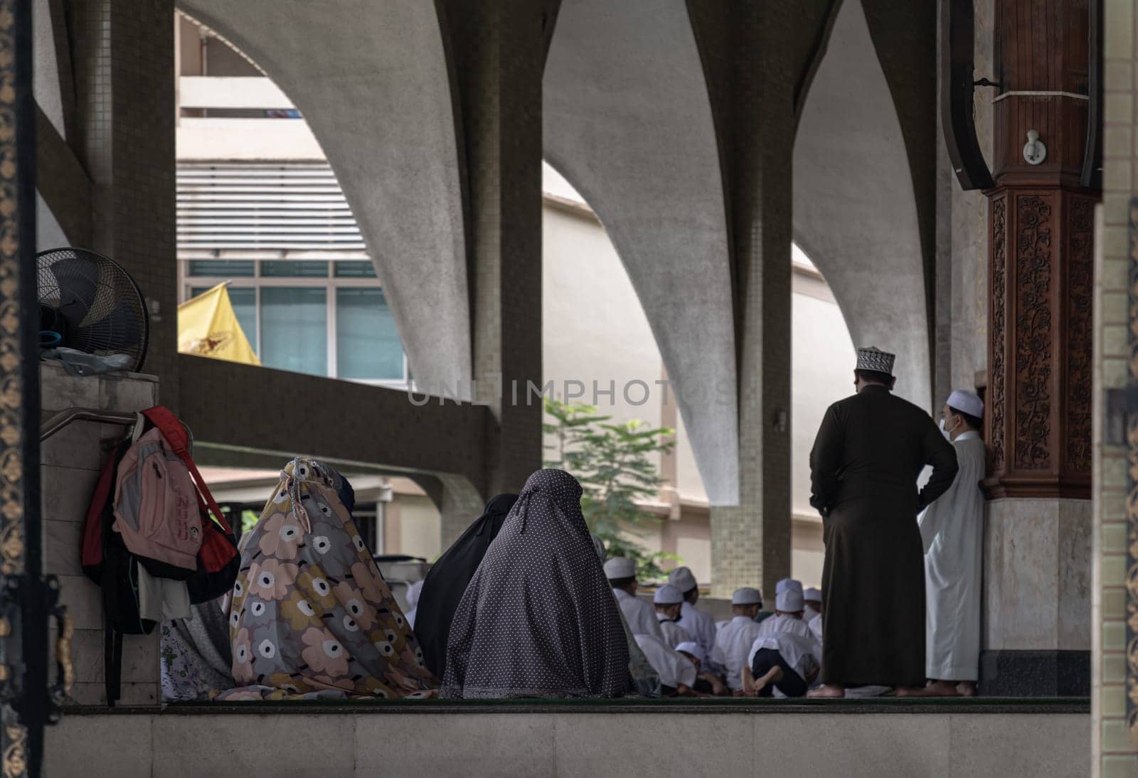Bangkok, Thailand - 28 May 2020 - Muslims women in hijab and boys are gathering to sit praying inside the mosque. The muslim prayer for god, Religions Islam, Space for text, Selective focus.