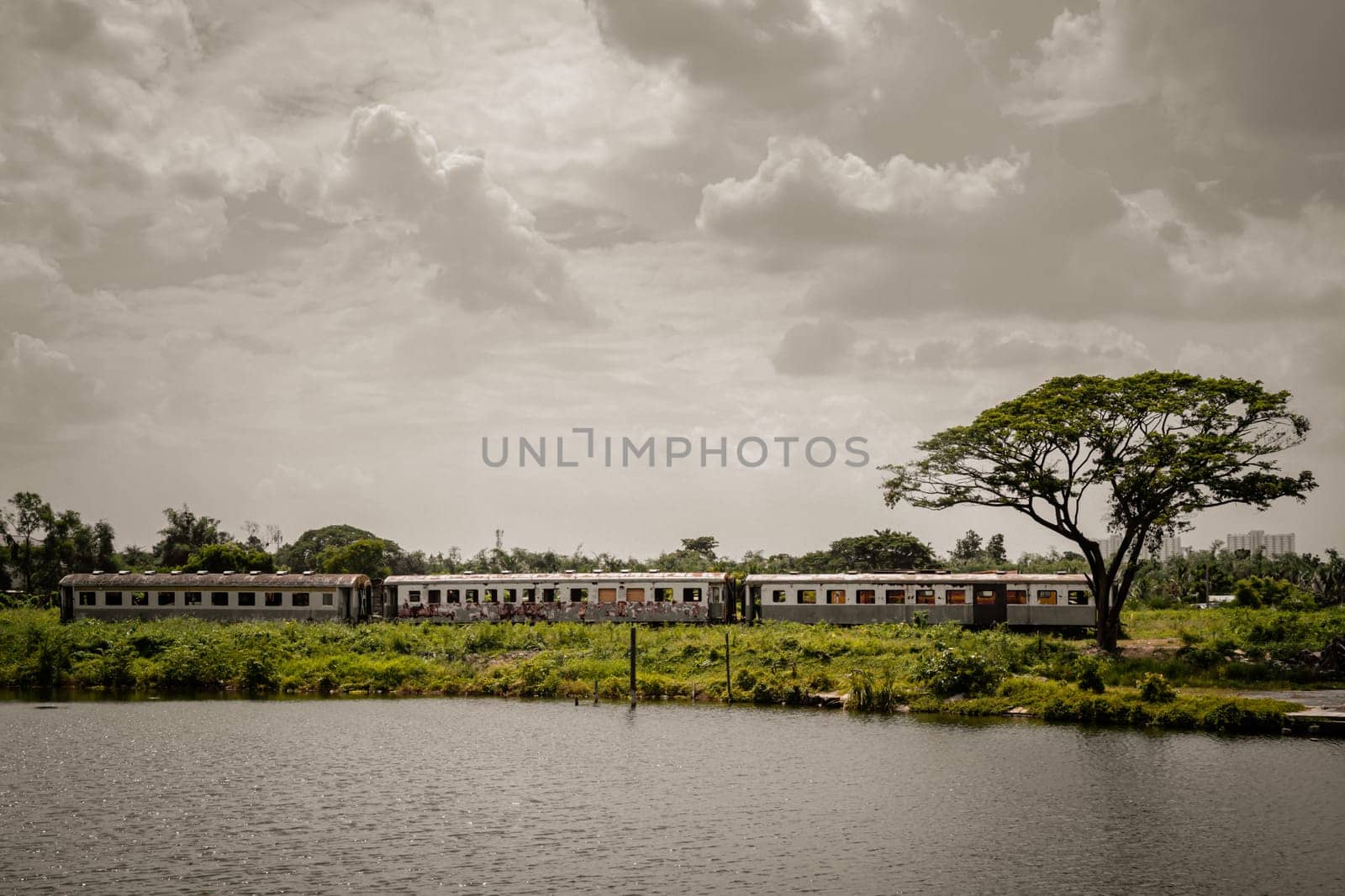 Bangkok, Thailand - May 28,2022 - View of vintage railroad container is parked in wasteland and swamp with sky background. The empty old rusty passenger train and abandoned, Space for text, Selective focus.