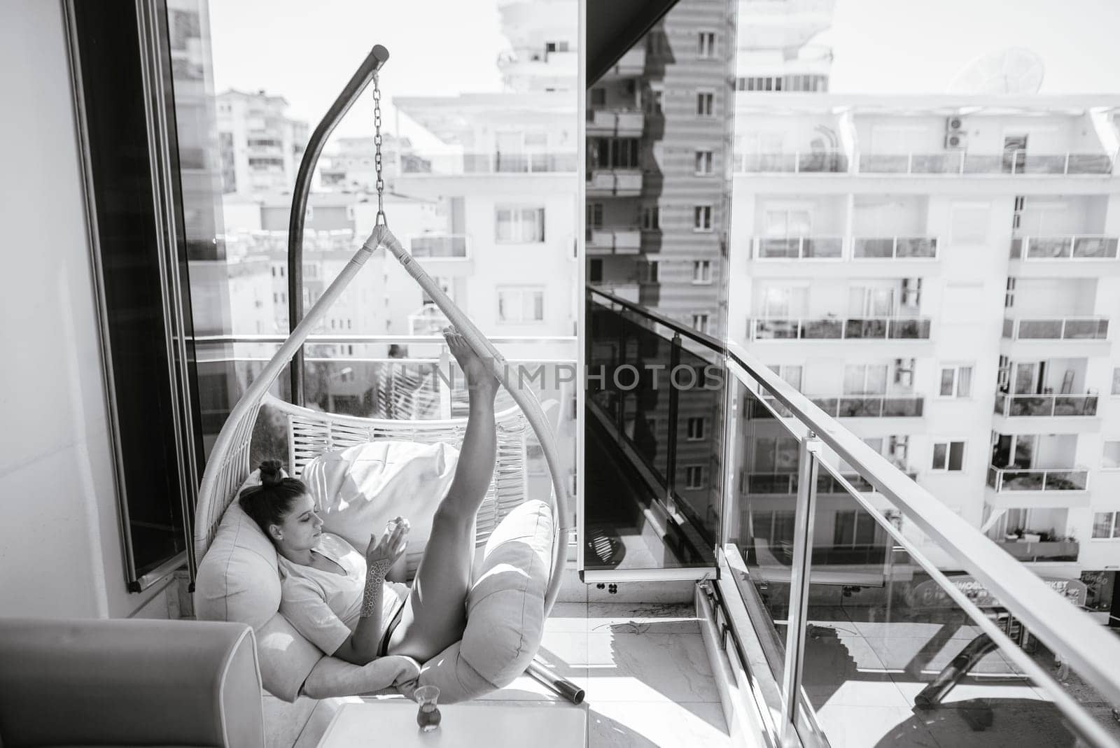 A serene and peaceful moment captured on a modern balcony, featuring a stylish hammock chair and stunning city views