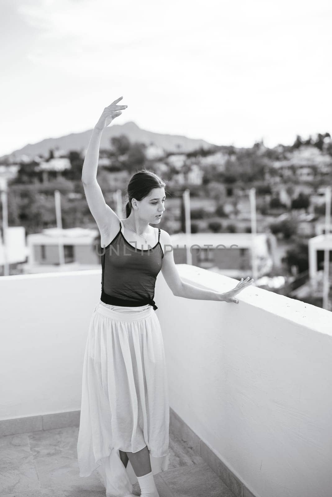 A graceful ballet dancer elegantly strikes a breathtaking pose on a stunning rooftop with scenic views all around