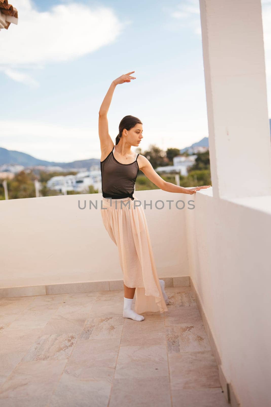 A graceful ballet dancer elegantly strikes a captivating and beautiful pose outdoors against a scenic backdrop