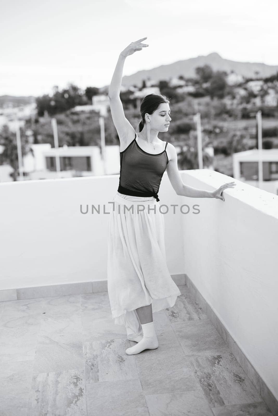 A graceful ballet dancer performs a stunning routine on a rooftop, merging art with breathtaking scenery