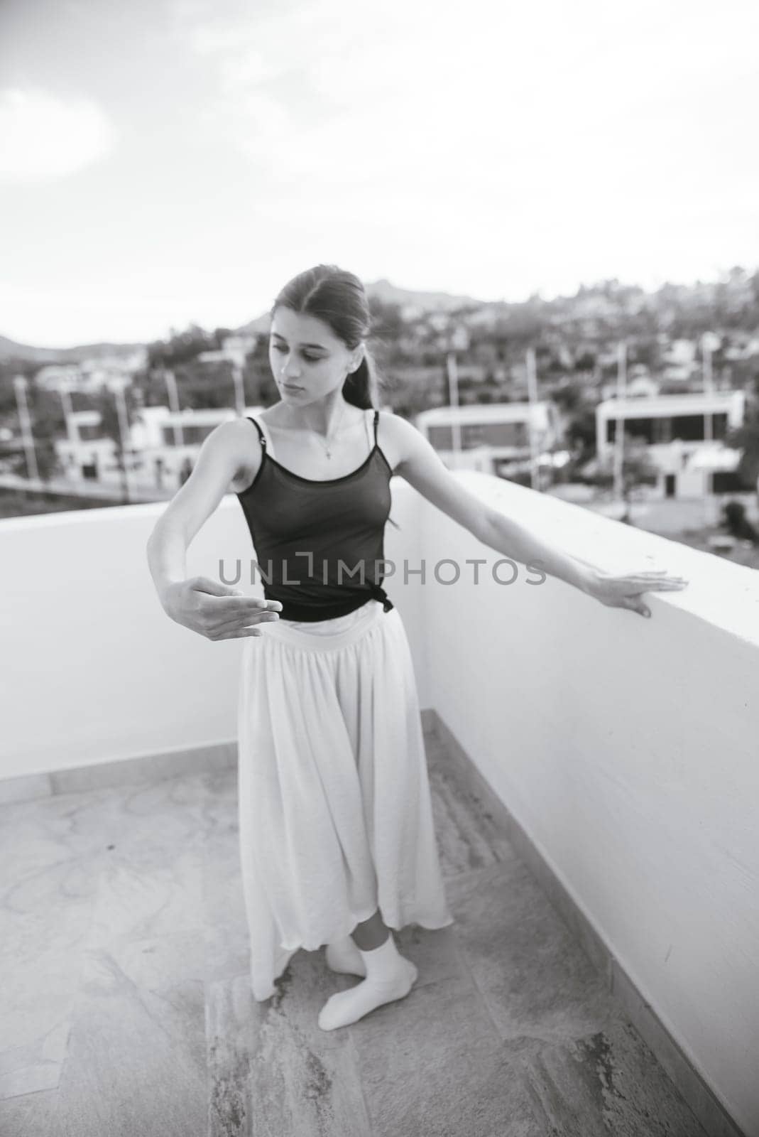 A graceful ballet dancer showcases her incredible talent on a scenic rooftop, beautifully captured in black and white