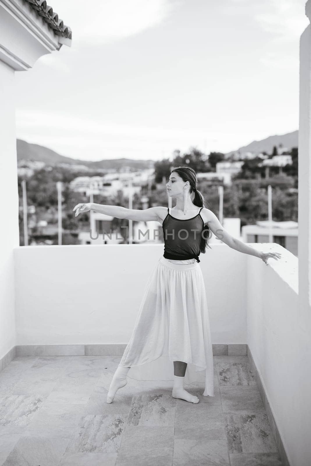 A skilled dancer elegantly strikes a poised pose on a balcony, enhanced by a stunning and picturesque backdrop