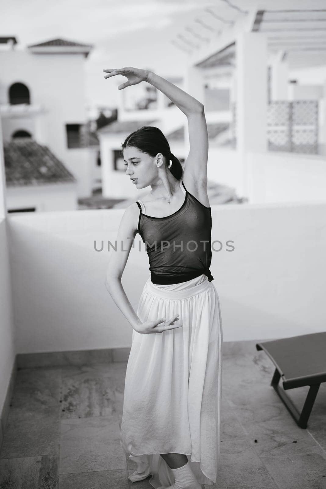 A dancer is striking a beautifully elegant pose on a balcony that features a stunning backdrop view