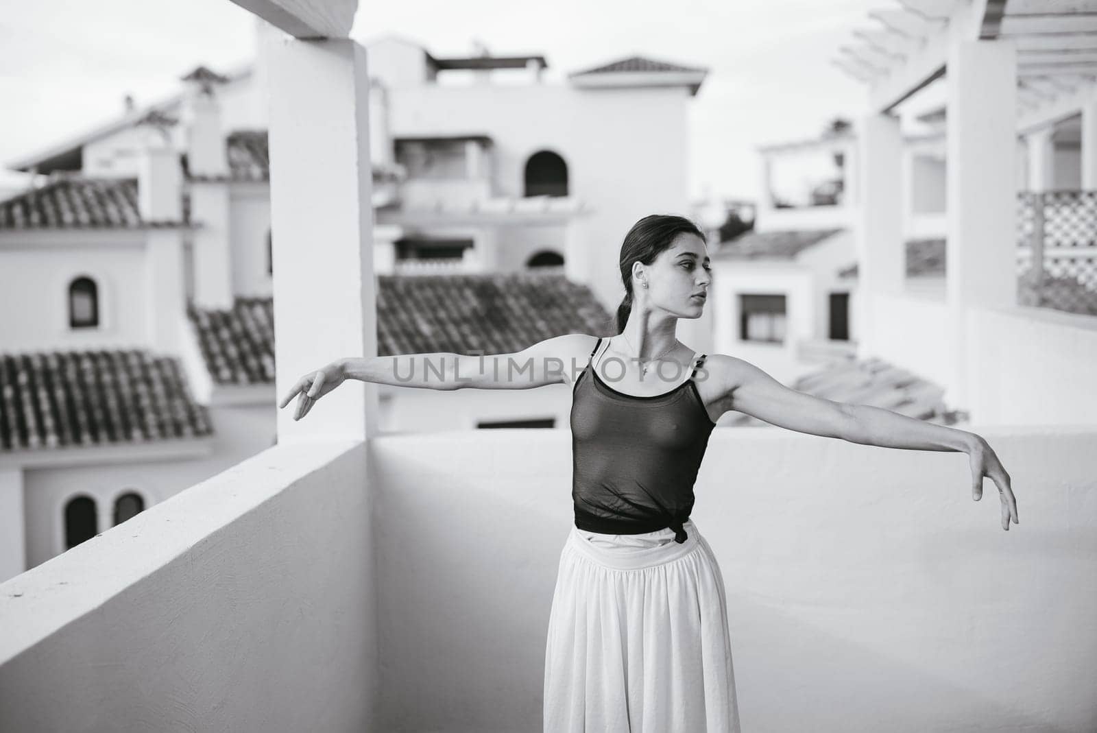 A poised dancer elegantly poses on a balcony, showcasing artistry and movement against a stunning backdrop.