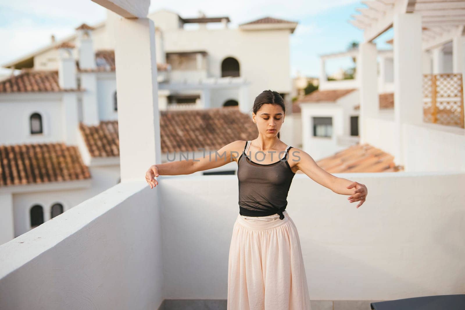 A talented dancer poses elegantly on a terrace, showcasing beauty against a stunning natural backdrop