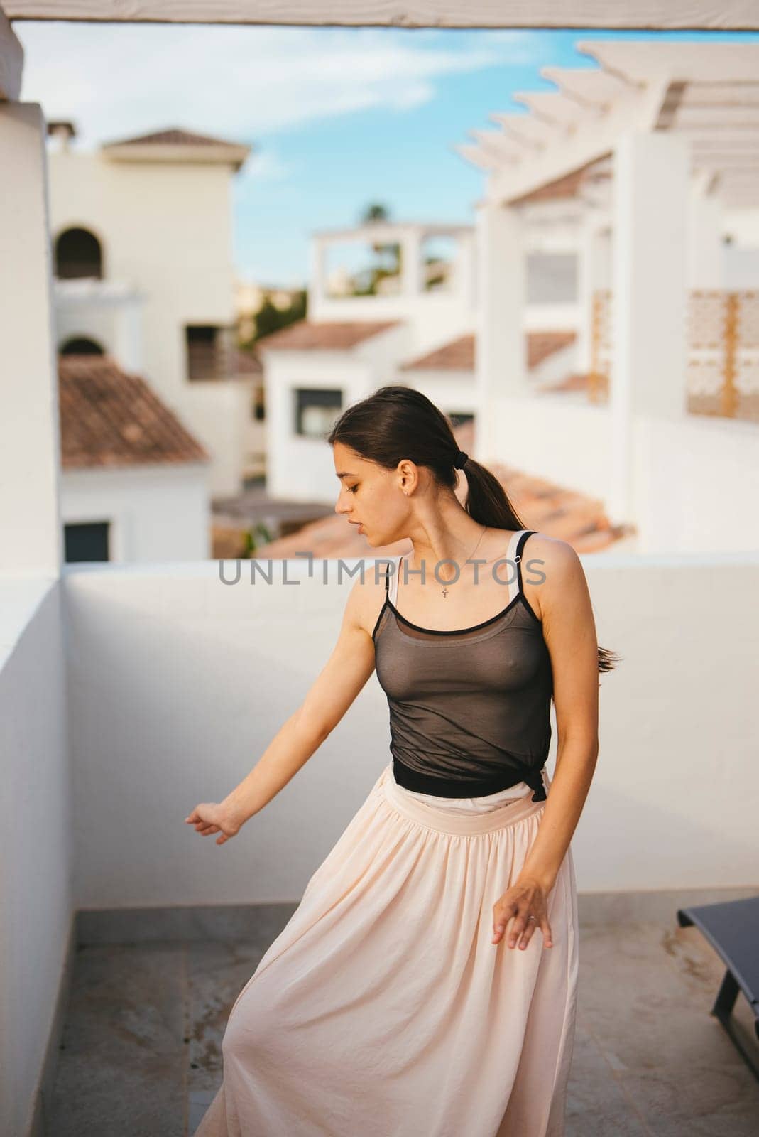 A joyful woman revels in a carefree moment, dancing freely on her balcony, embraced by stunning architecture