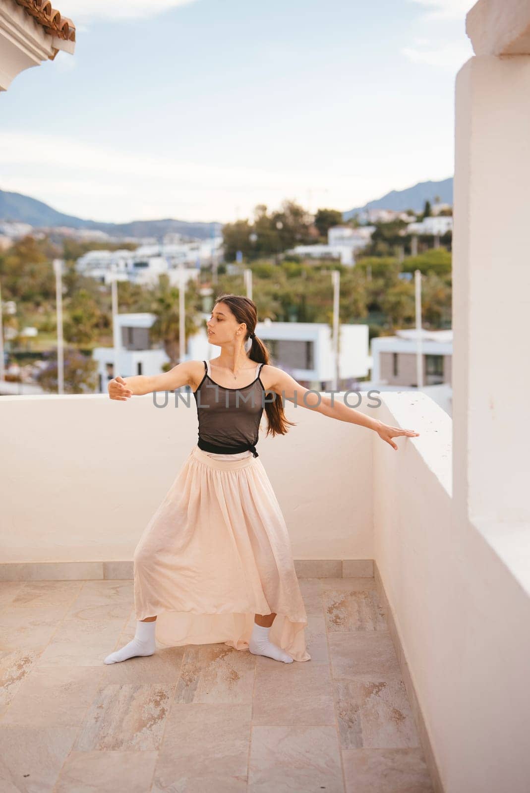 A skilled dancer poses gracefully outdoors, displaying elegance and beauty against a stunning scenic background