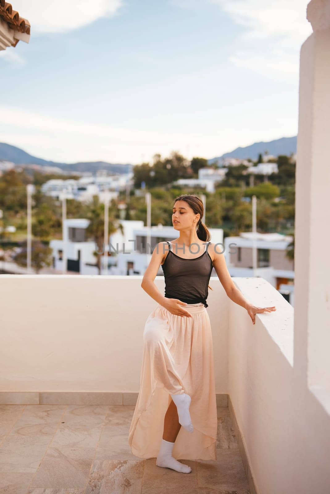 A serene moment of a model in a flowing skirt on a balcony, surrounded by nature, creating a picturesque scene