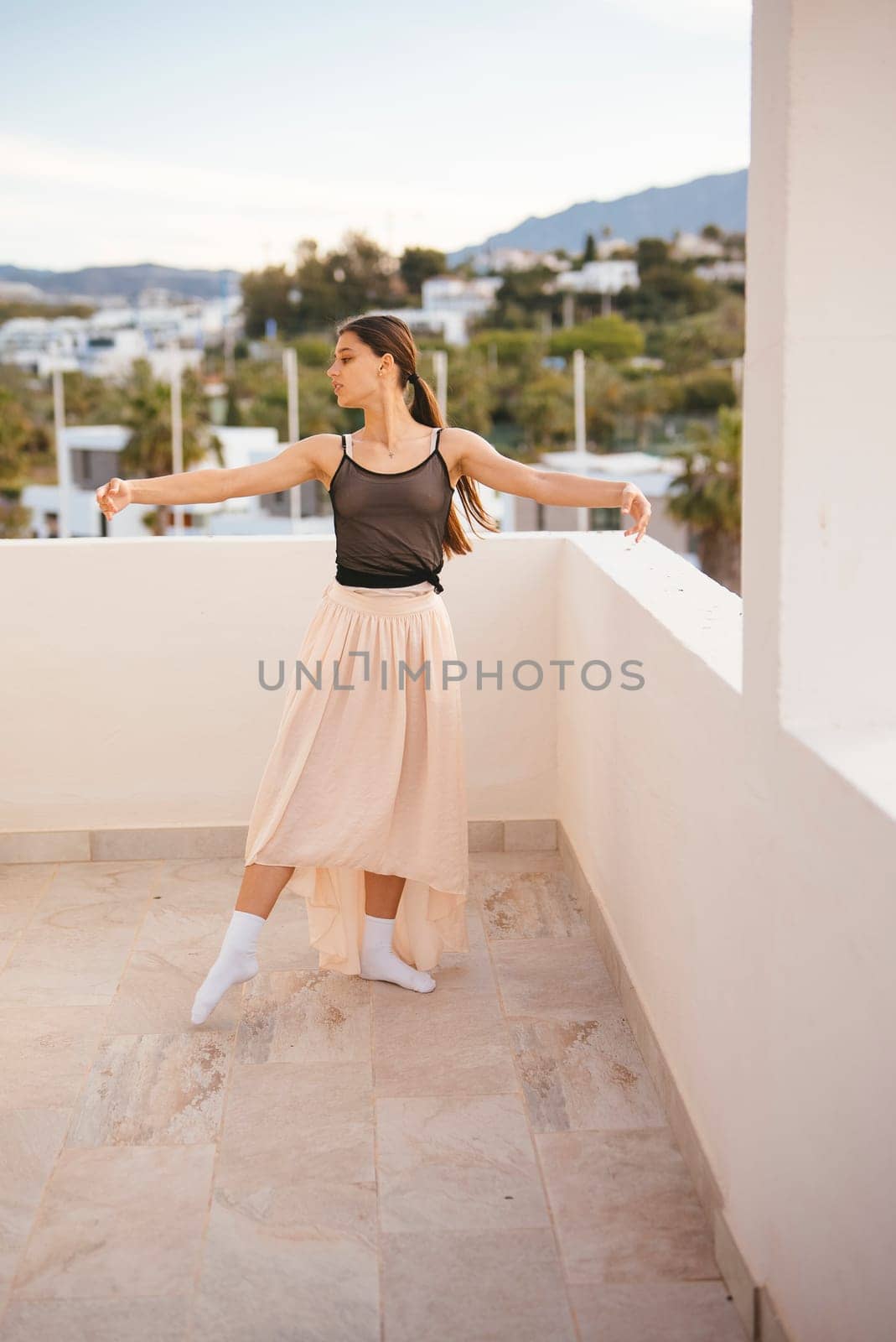 A talented ballet dancer exhibits grace, elegance, and poise while performing on a tranquil rooftop setting