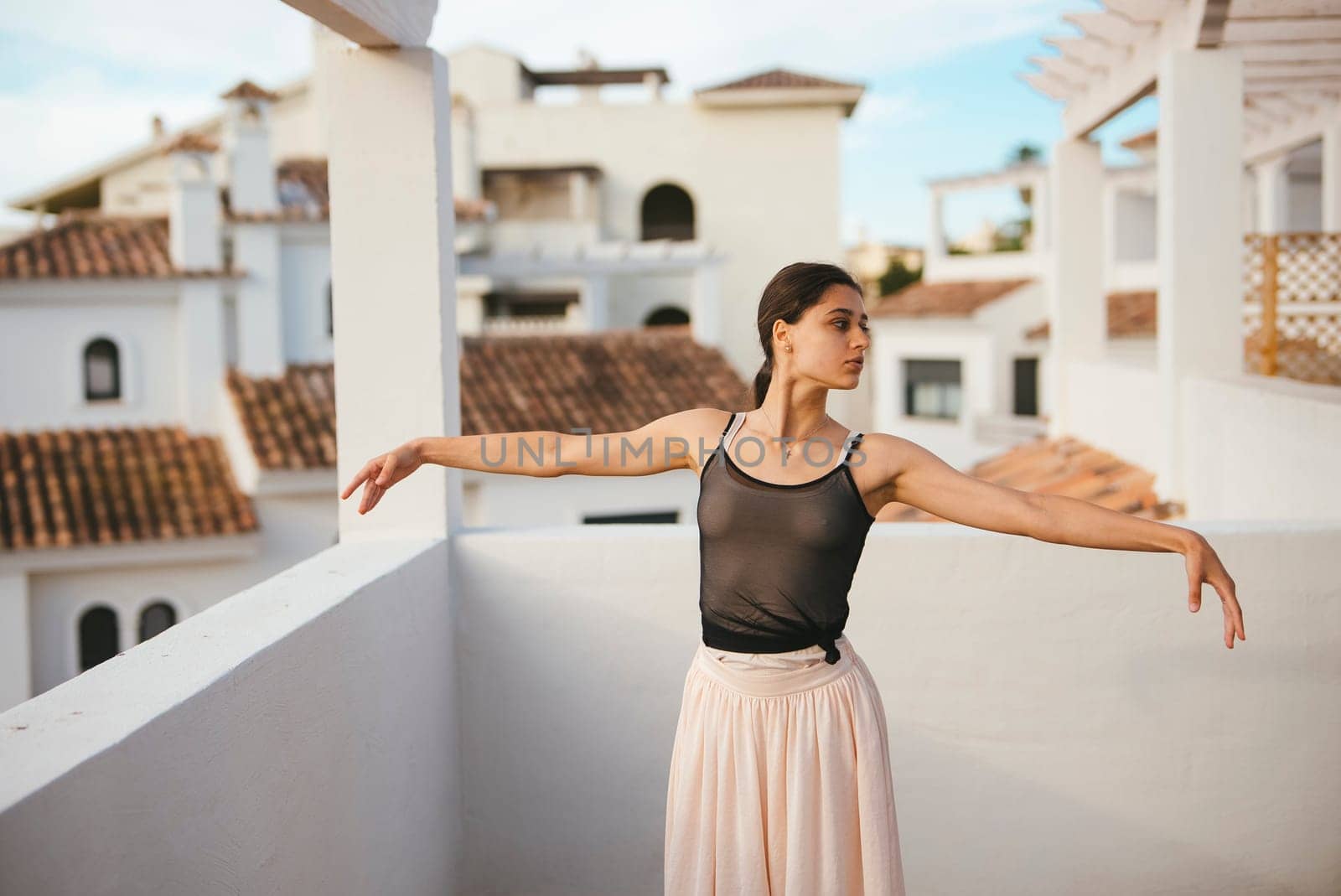 A graceful dancer showcases her artistry on a rooftop, surrounded by stunning architecture and a bright blue sky