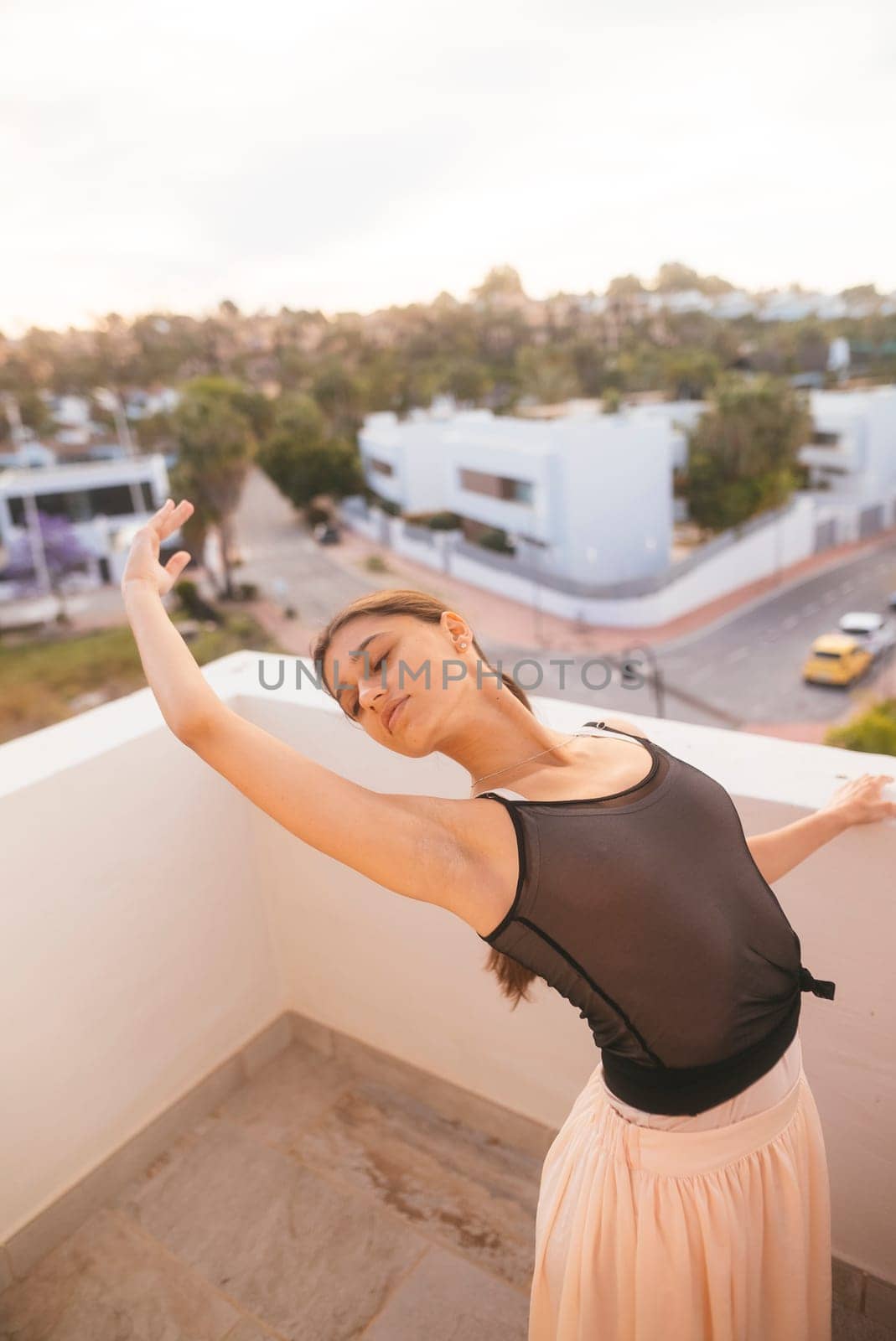 A dancer showcases elegance and freedom on a balcony at sunset, embodying beauty and fluid movement in every pose
