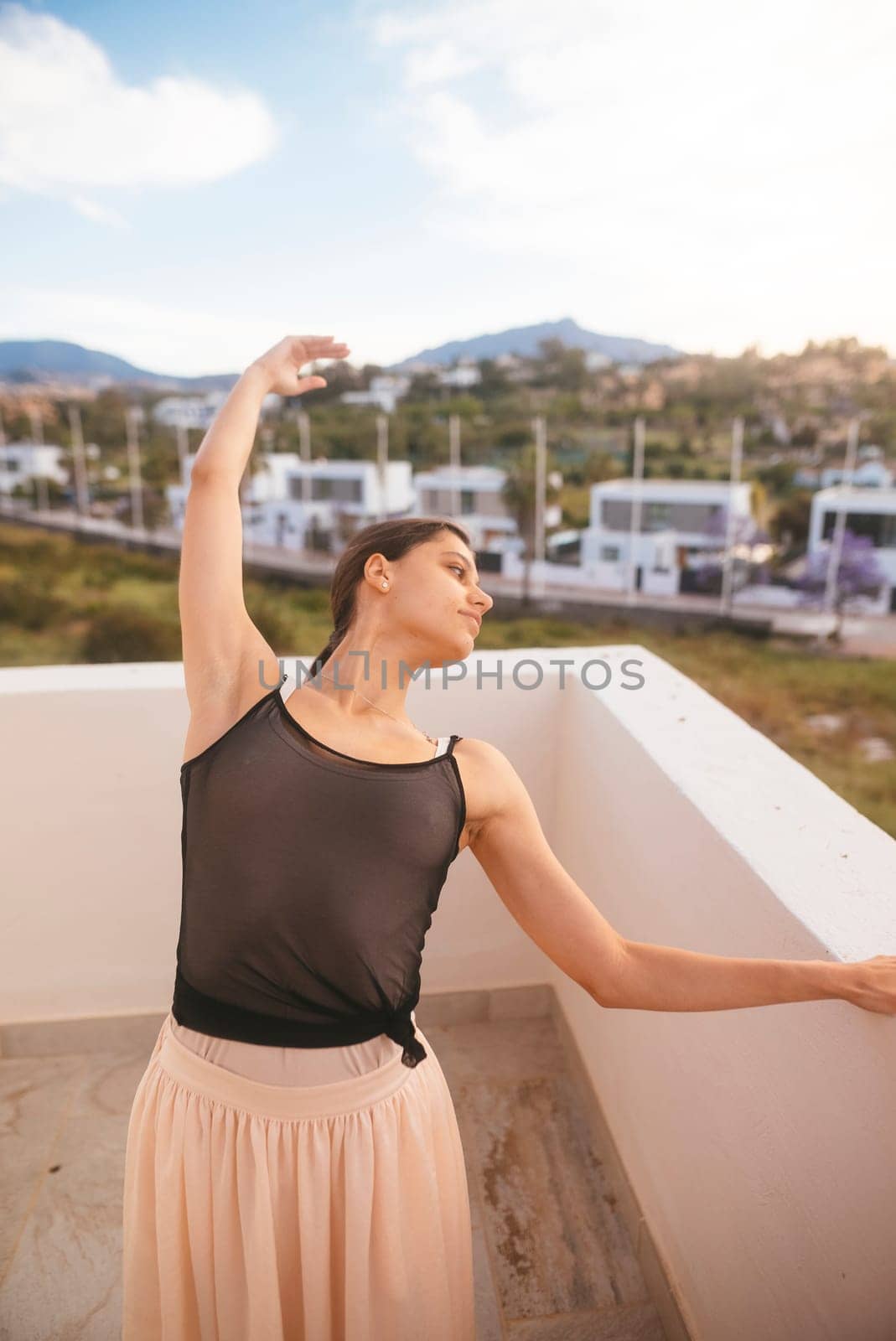 A talented dancer strikes a beautiful pose on a balcony, blending elegance with the natural beauty around her