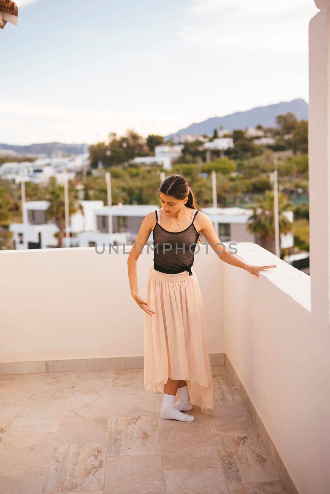 A graceful woman dressed in an elegant skirt enjoys a beautiful and captivating view from a modern balcony