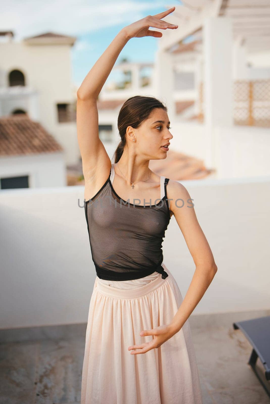 A skilled dancer elegantly poses on a bright, sunny rooftop, showcasing her poise, artistry, and creativity