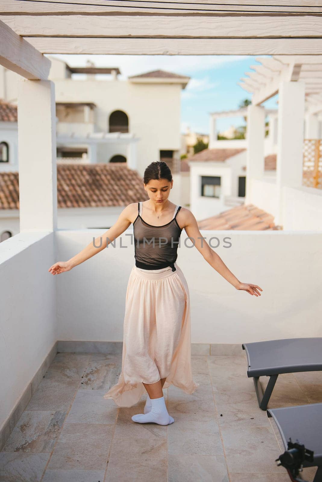 A graceful dancer in a flowing outfit skillfully performs on a beautiful balcony with stunning architecture
