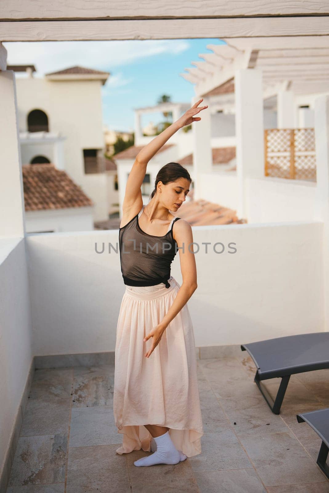 A graceful dancer elegantly showcases her impressive motion and artistry on a serene and picturesque balcony