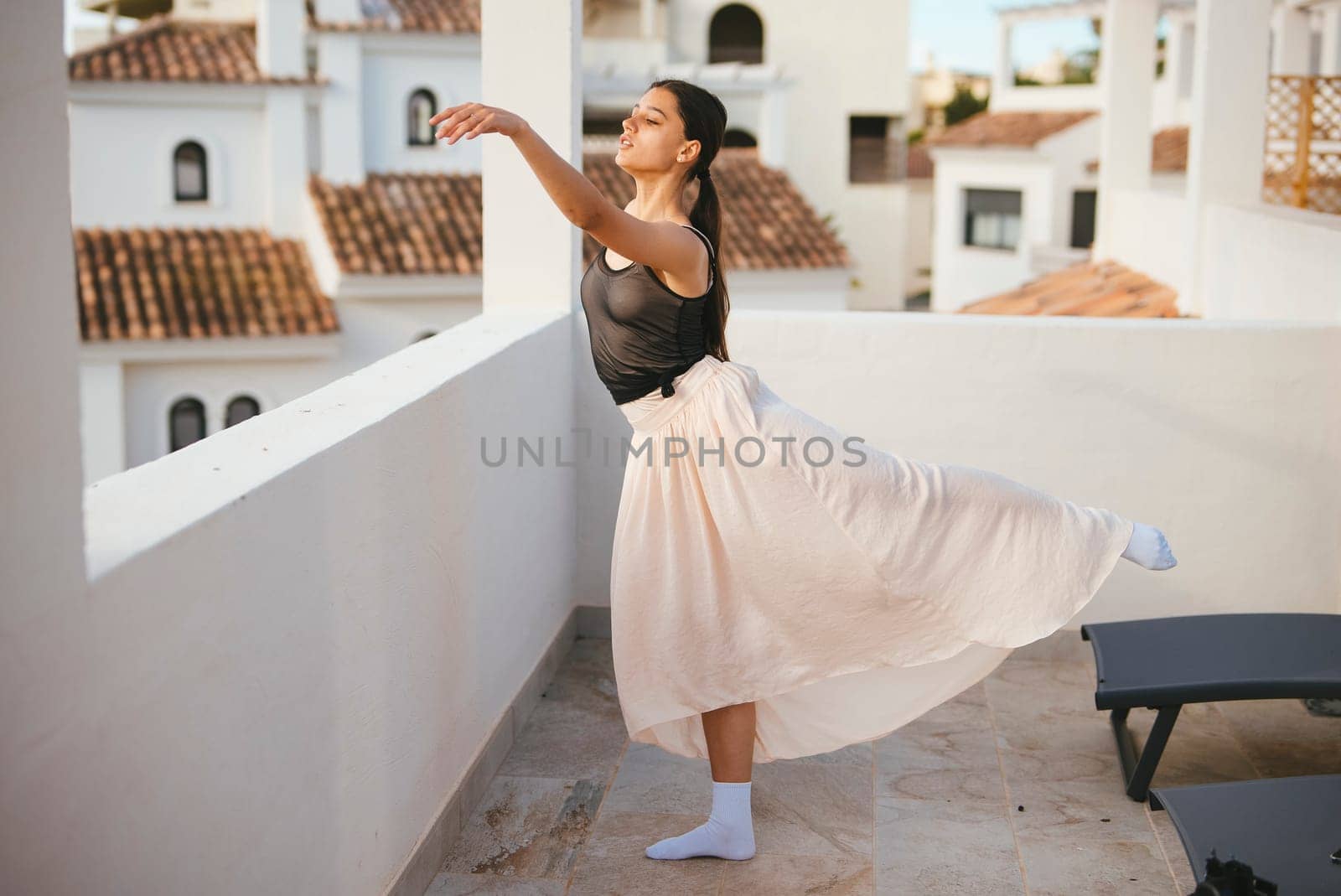A talented dancer poses elegantly on a balcony, showcasing beauty and grace against a bright backdrop