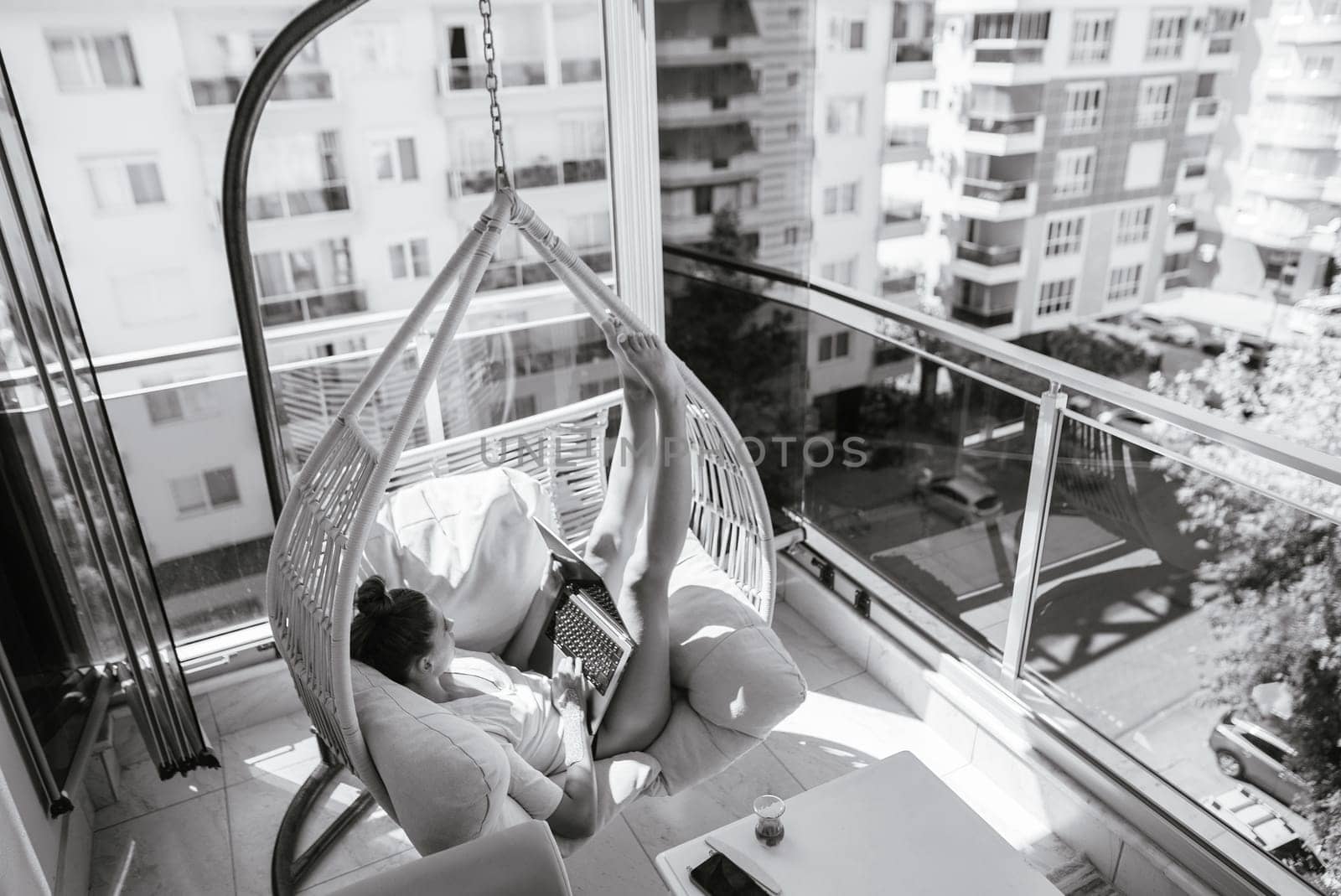 A serene and peaceful moment beautifully captured of a person lounging in a stylish hanging chair on a cozy balcony