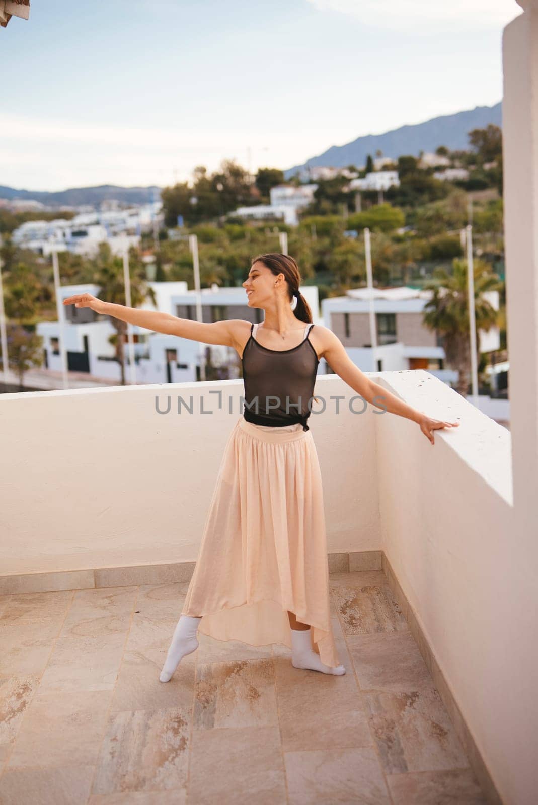 A graceful dancer confidently strikes a stunning pose on a balcony, complemented by a breathtaking mountain backdrop