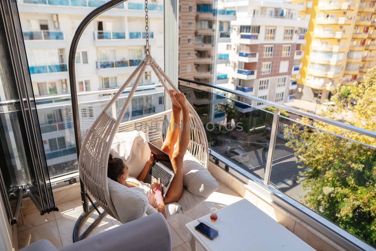 A person is happily enjoying their leisurely time while lounging in a stylish hammock situated on a modern balcony
