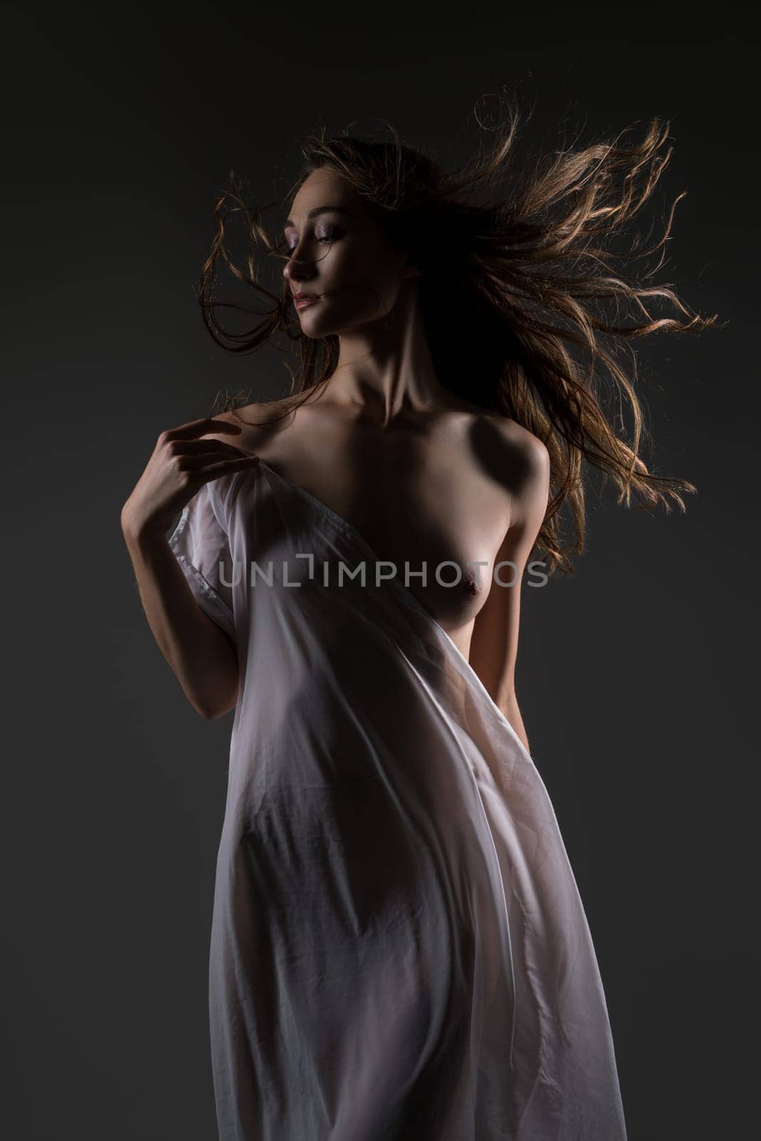 Slim pretty longhaired brunette white cloth draped over her body view against gray background