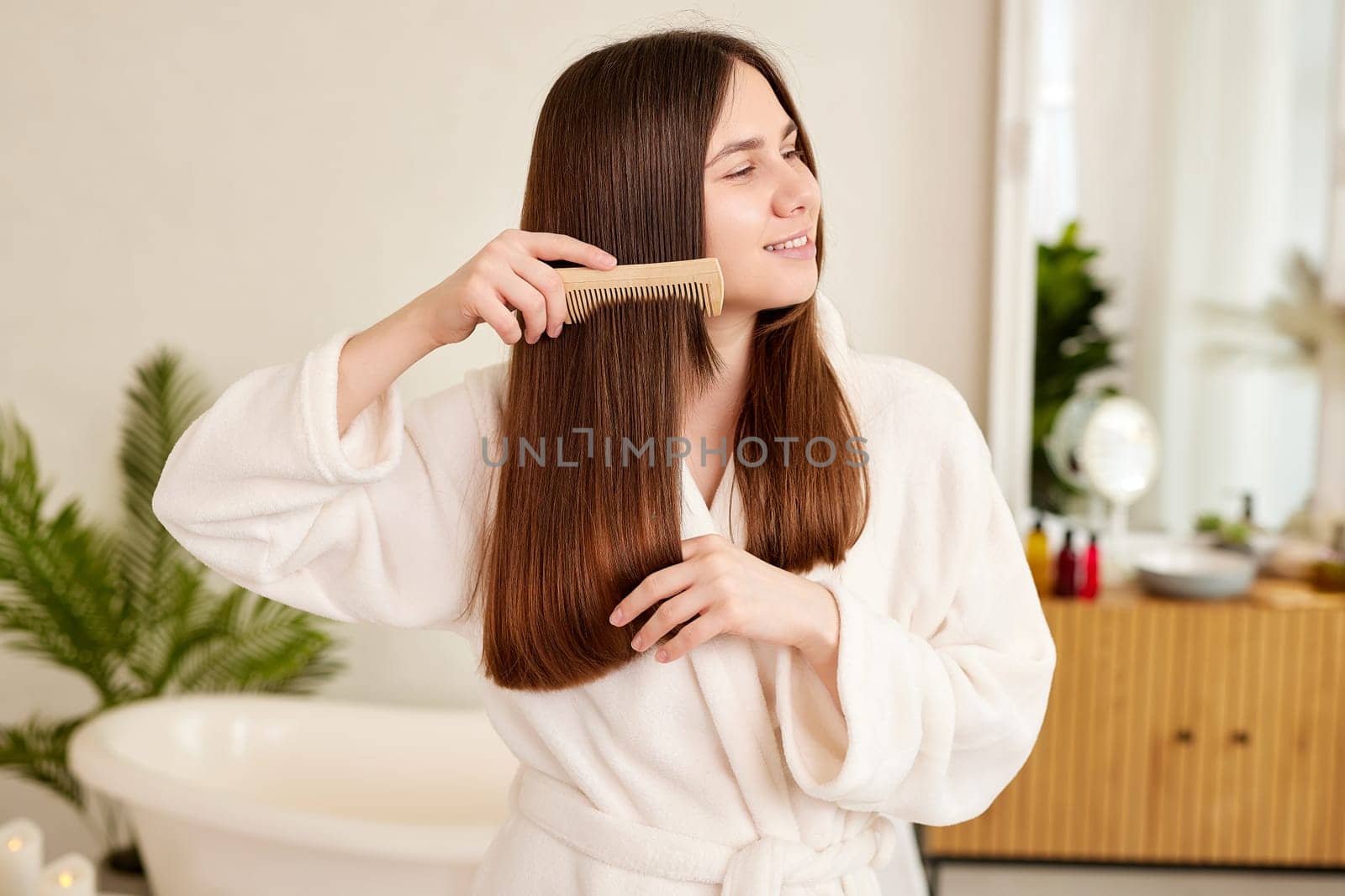 a young girl in a white coat takes care of her hair at home, Hair care concept