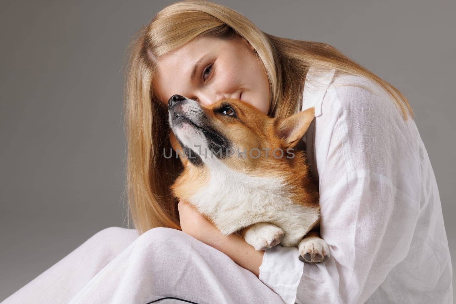 Woman lovingly hugging corgi dog, they look contented and happy. animal care concept