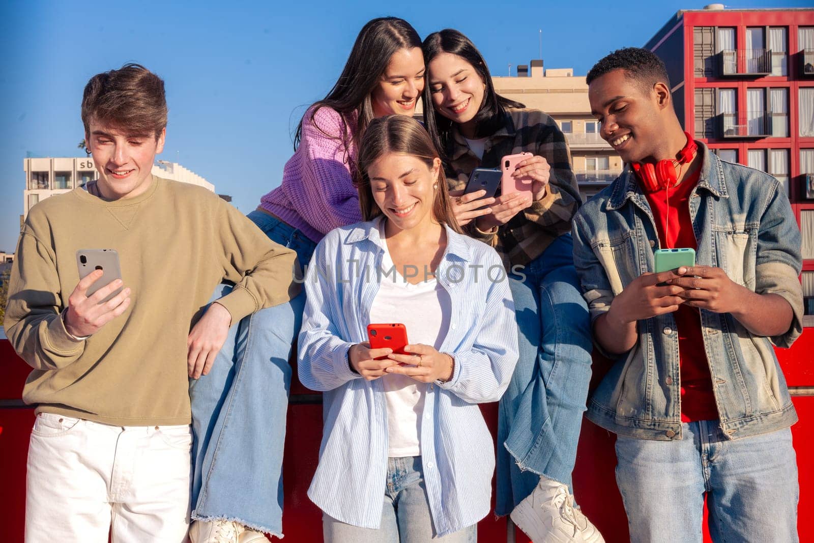 Group of friends using looking at their smartphones Multiracial teenagers browsing the internet with mobile phone on campus