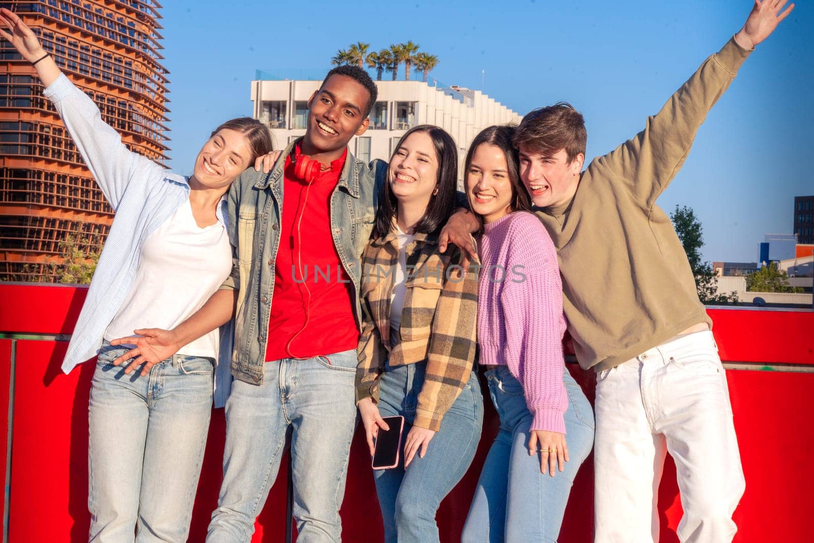 Five multiracial friends smiling and looking at the camera with cheerful expressions. Enthusiastic young people gathered looking at camera