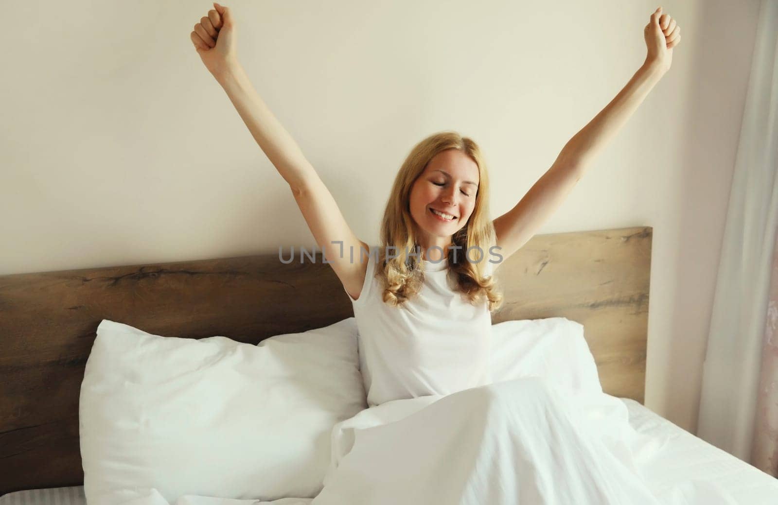 Healthy sleep, relaxed woman wakes up lying on the bed in bedroom at home