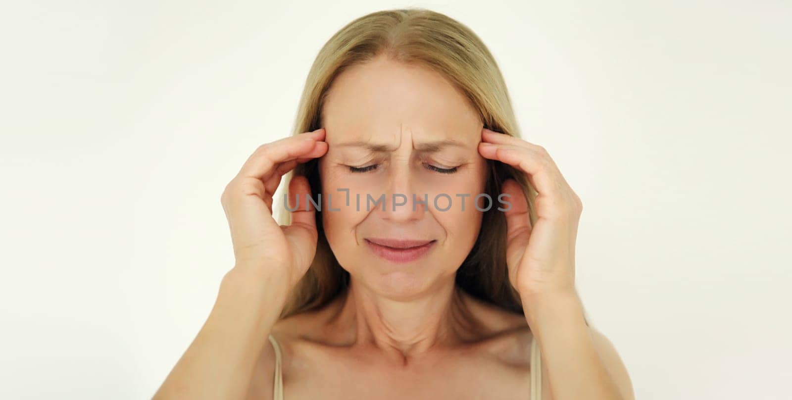 Exhausted tired mature woman touching head, suffering from headache, stress, fatigue, temples pain, migraine, loud noise, tension on white background