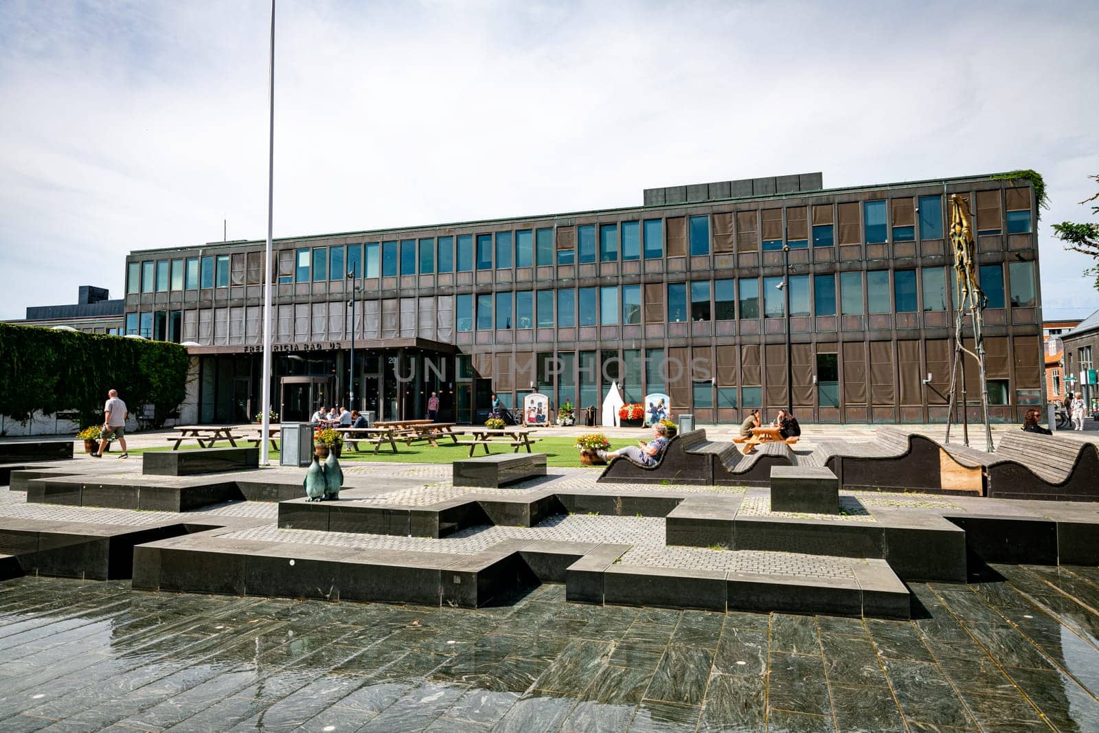 Fredericia, Jutland, Denmark, aug 13, 2024 - Contemporary town hall and square with people sitting on banks