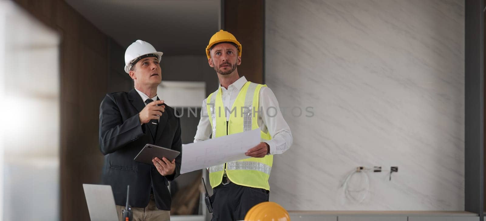 Diverse Team of Specialists Use Laptop on Construction Site. Real Estate Building Project with Engineer Investor and Businessman Checking Area, working on Civil Engineering, Discussing Strategy Plan by wichayada