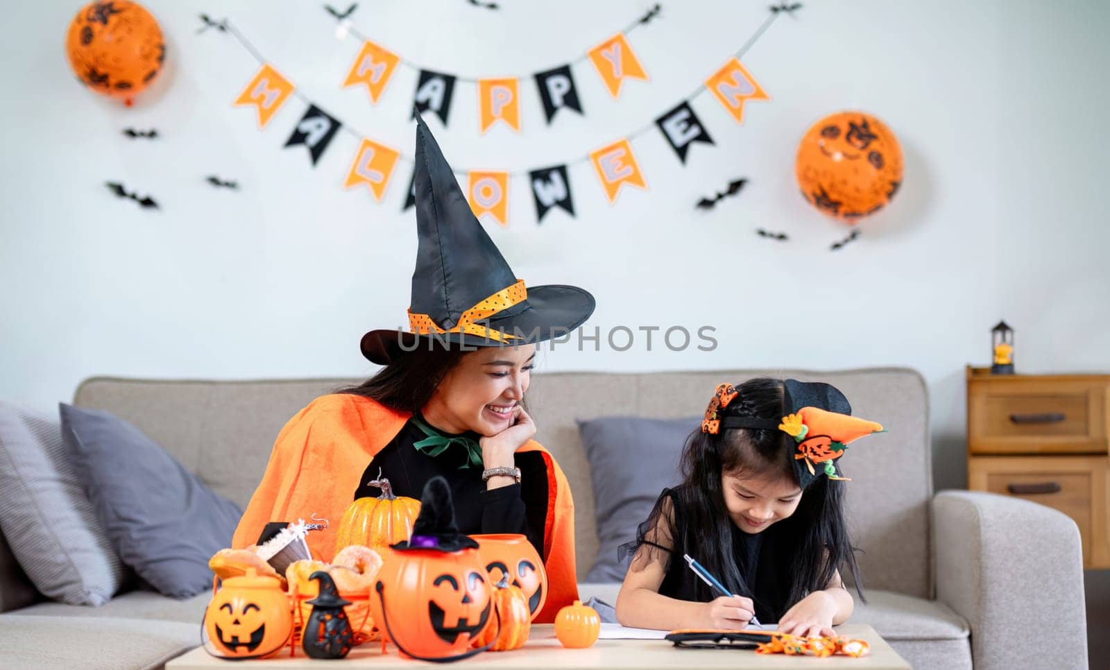 Family mother and daughter prepare decorations for Halloween at home. Draw pictures and cut paper together. and participate in creativity by wichayada