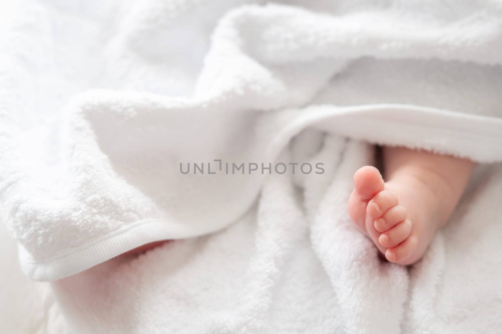 A heart-touching portrayal of pure innocence as a newborn baby's foot tenderly peeks out from a soft white towel