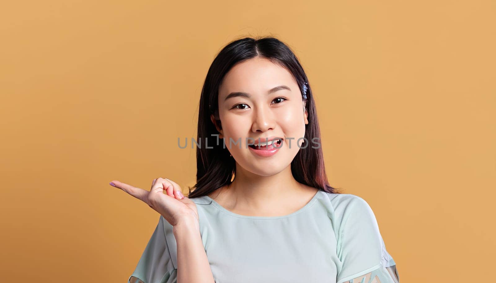 Portrait of young beautiful Asian lady smiling with cheerful expression, shows something amazing at blank space banner background poster wallpaper. AI Generative. by Benzoix
