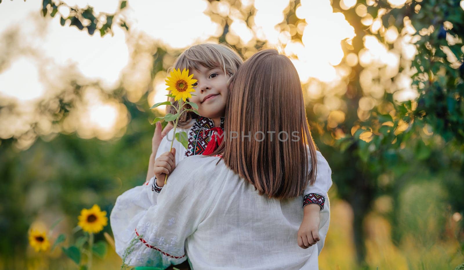 Portrait of beautiful family - 4 years old boy with sunflower, mother in garden by kristina_kokhanova